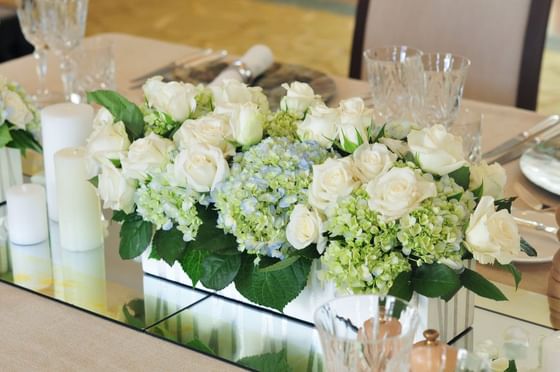 A floral centerpiece featuring white roses and blue hydrangeas, set on a elegantly dressed dining table at Park Hyatt Saigon