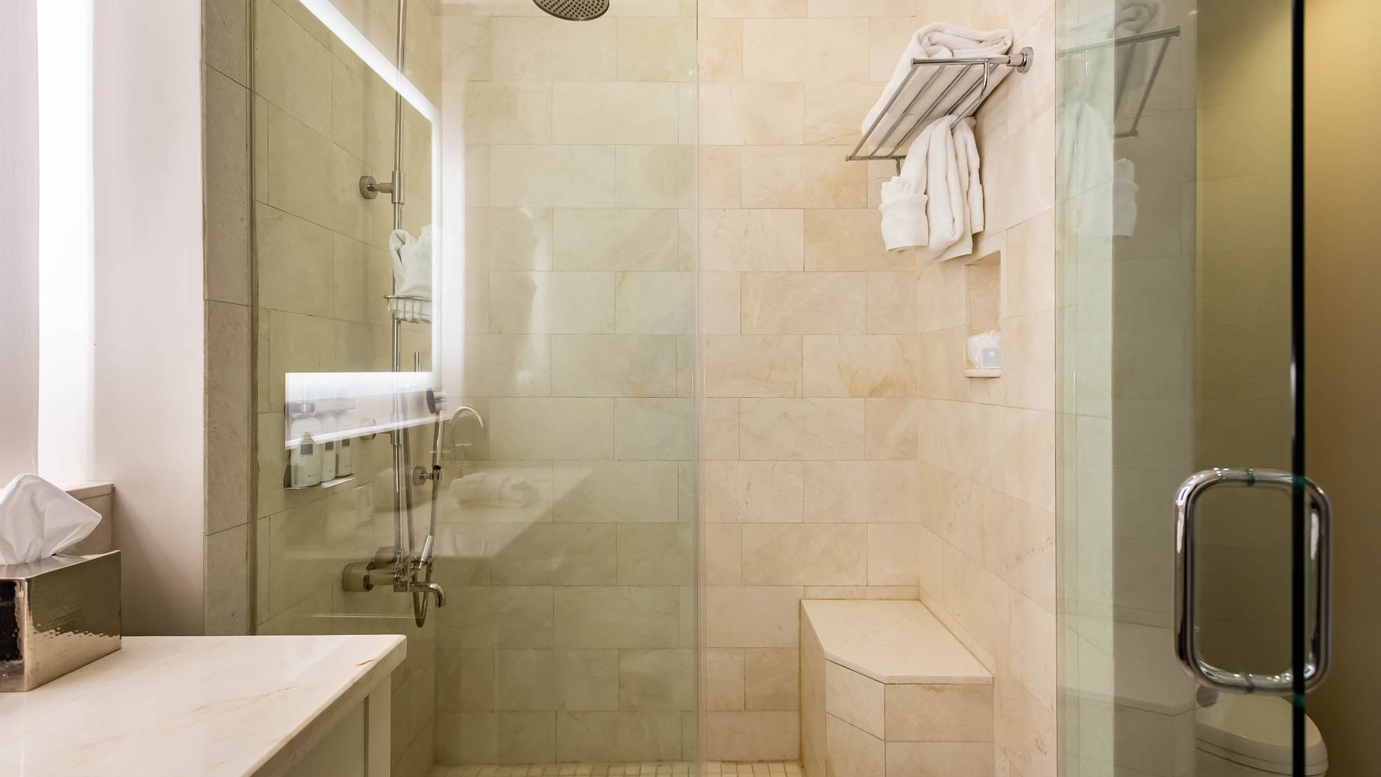 Clean, tiled bathroom with shower and towels in suite at The Pearl Hotel, Rosemary Beach.