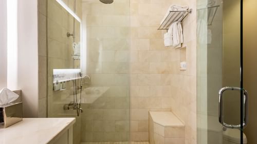 Clean, tiled bathroom with shower and towels in suite at The Pearl Hotel, Rosemary Beach.