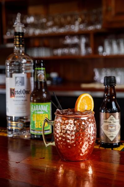 A classic Moscow Mule in a hammered copper mug garnished with an orange slice at the bar of Lake Placid Club Grandview