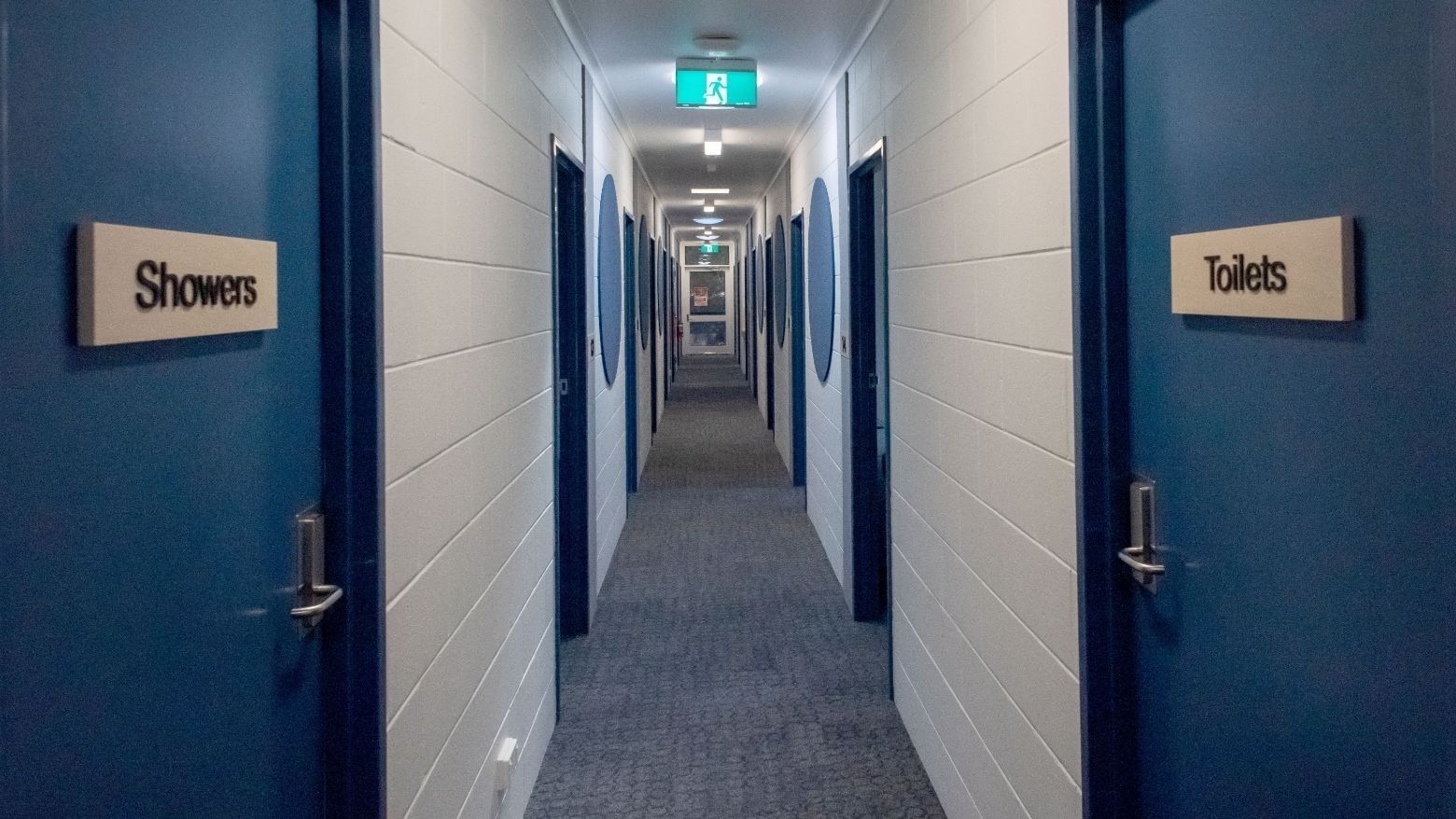Hallway with blue doors labeled Showers and Toilets at La Trobe University - Orde House.