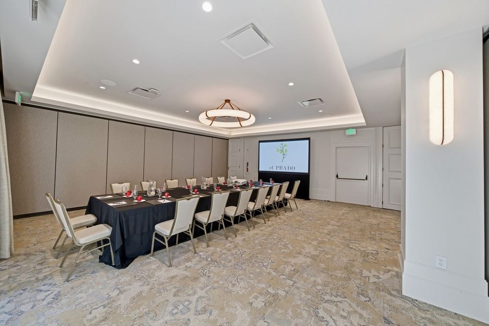 meeting room set up at el PRADO with a screen at the end of the table reading el PRADO with a yellow flower