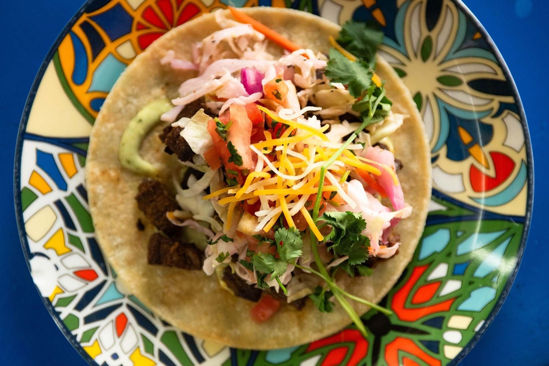 A taco on a colorful plate with various toppings