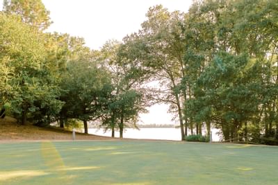 golf course with trees and a lake