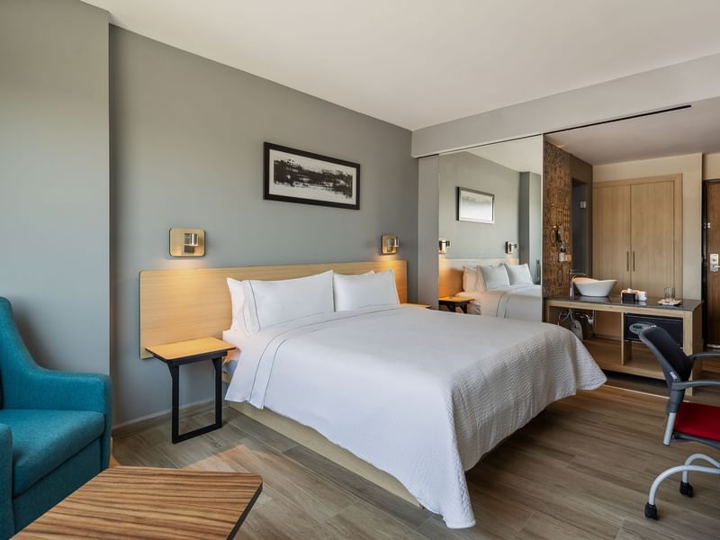 King-sized bed featuring modern decor and wooden flooring in Standard King Room at Gamma Hotels