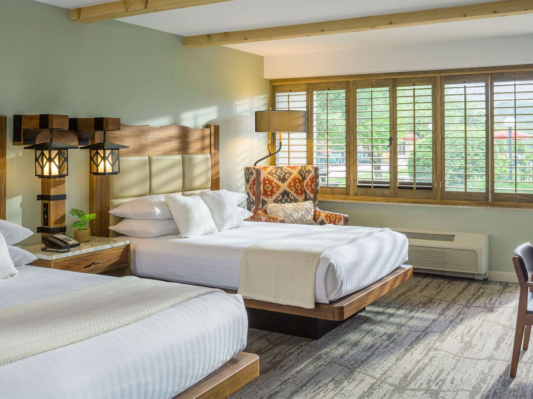 Hotel guest room with two queen size beds and armchair.