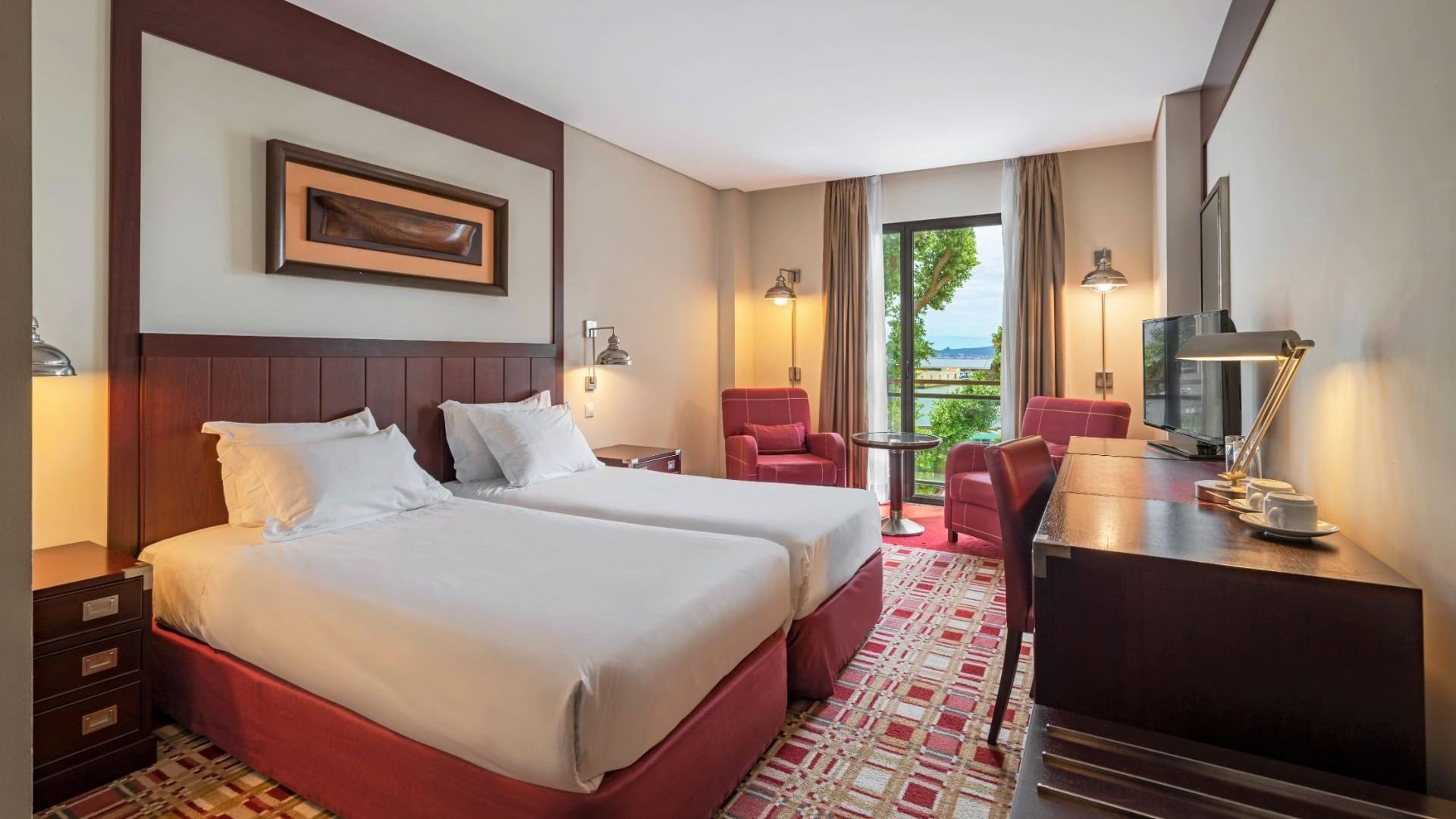 Two beds, work desk with lamp, coffee table & armchairs in Twin Suite at Hotel do Canal