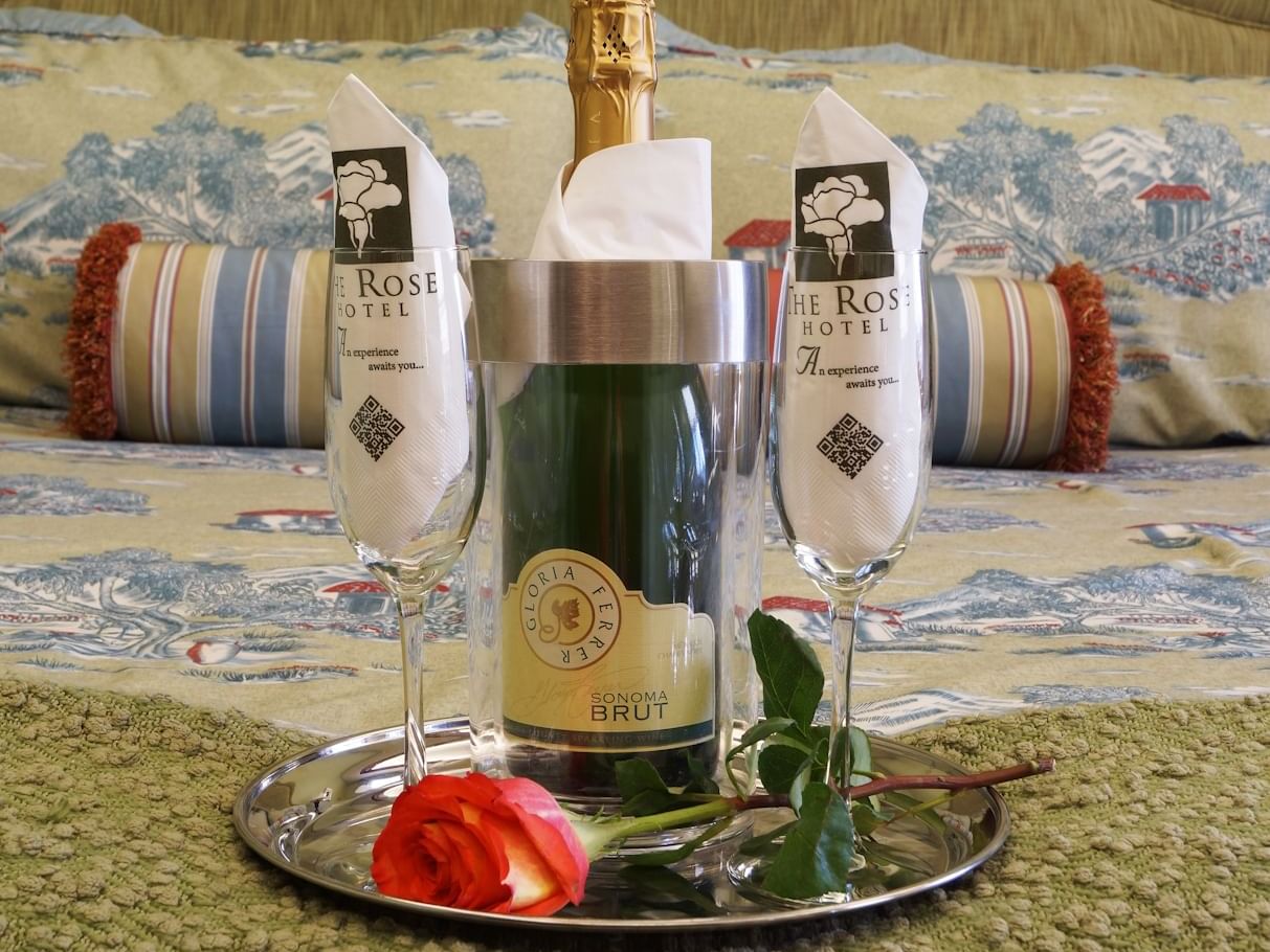 Bottle of champagne with two glasses on a silver tray, accompanied by a rose at The Rose Hotel