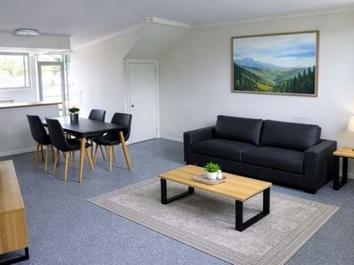 Living room with couch, coffee table, dining set, and TV at UniLodge SCU Lismore - Sirius.