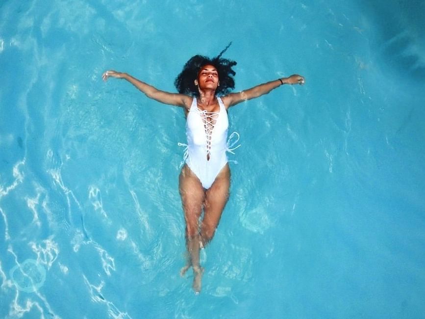 A woman in white bikini floating on water at Amora Hotel