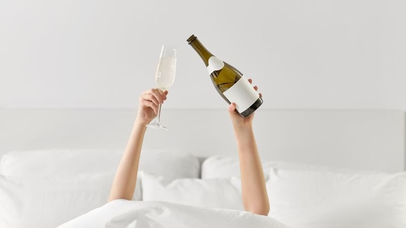 A person holding a glass of sparkling wine in one hand and a bottle in the other at Mercure Hotel Townsville