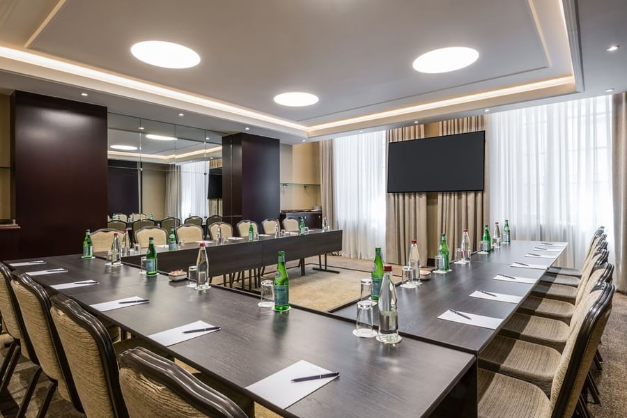 Moderne vergaderzaal met U-vormige tafelopstelling, waterflessen en flatscreen bij Warwick Brussels Bruxelles