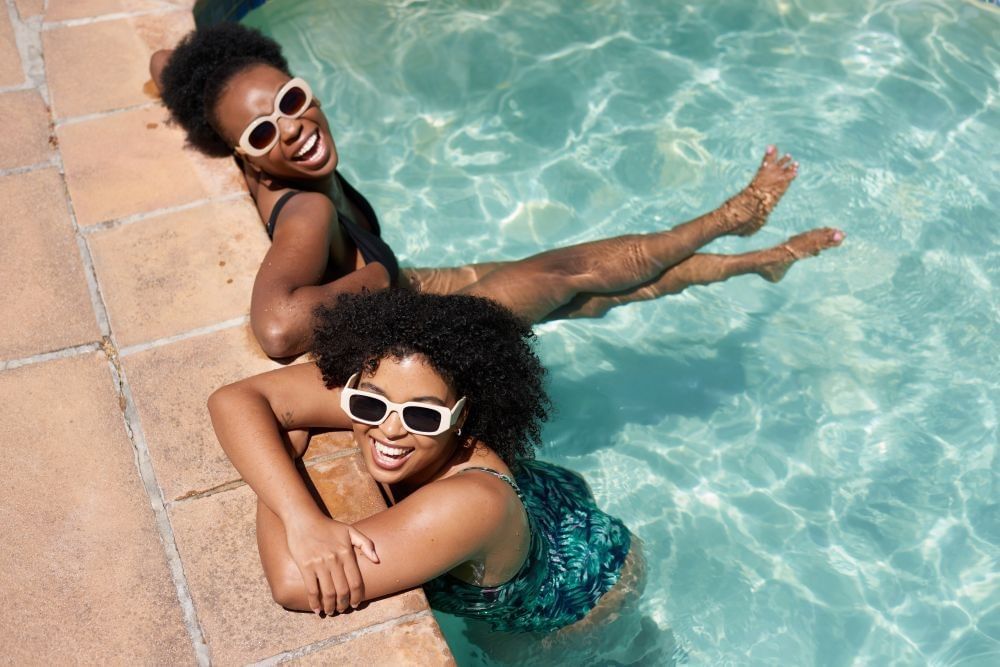 Two laughing women in sunglasses lounging in a pool. 