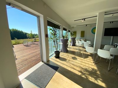 T2 interior with seating, plants, and an open door leading to a wooden deck at Avaneo Hotel, showcasing hotel images