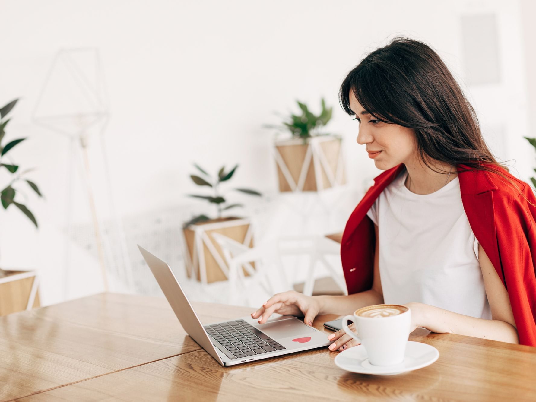 A lady on a laptop having a cup of coffee at Originals Hotels