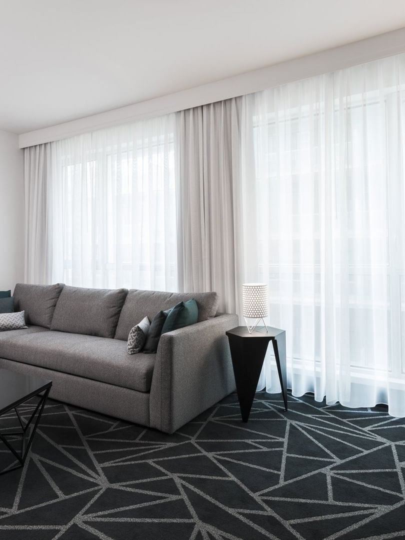 Salon de la suite junior avec un canapé près des grandes fenêtres à Warwick Le Crystal