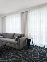 Salon de la suite junior avec un canapé près des grandes fenêtres à Warwick Le Crystal