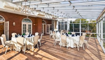 Glass Terrace featuring round dining tables under a glass ceiling surrounded by brick walls at Avon Old Farms Hotel