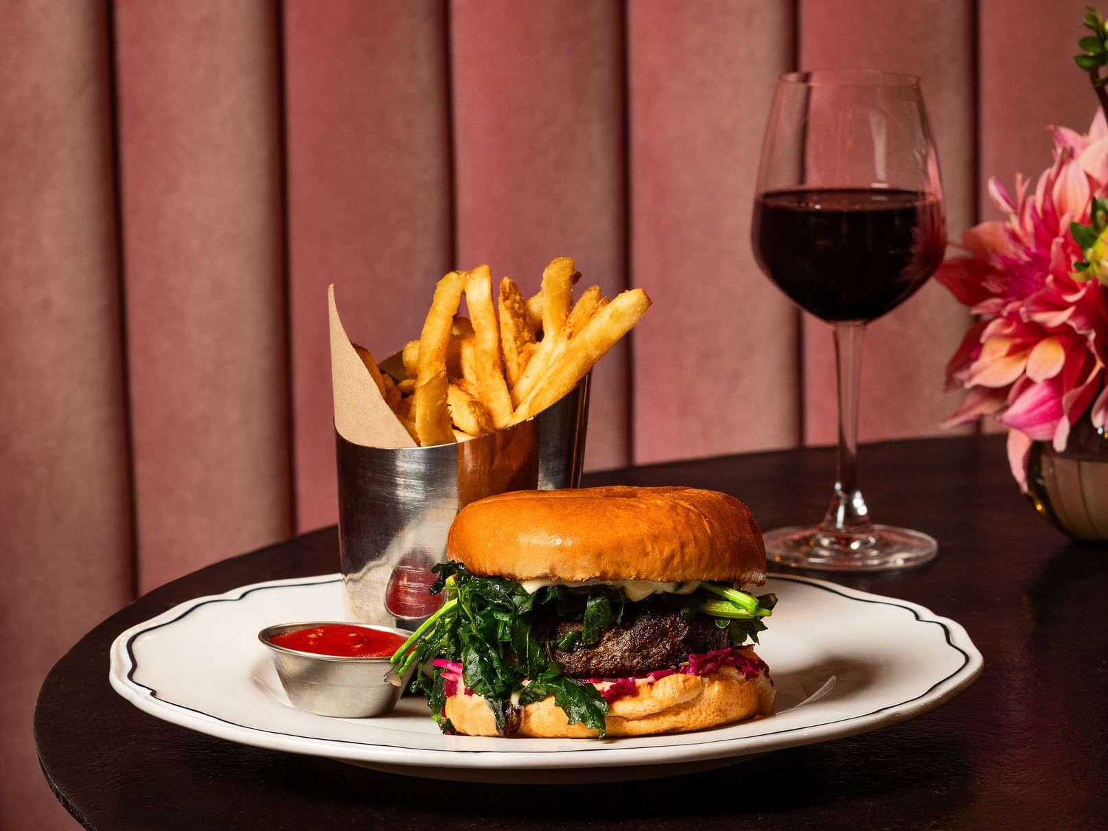 Burger with fries and a glass of wine on table