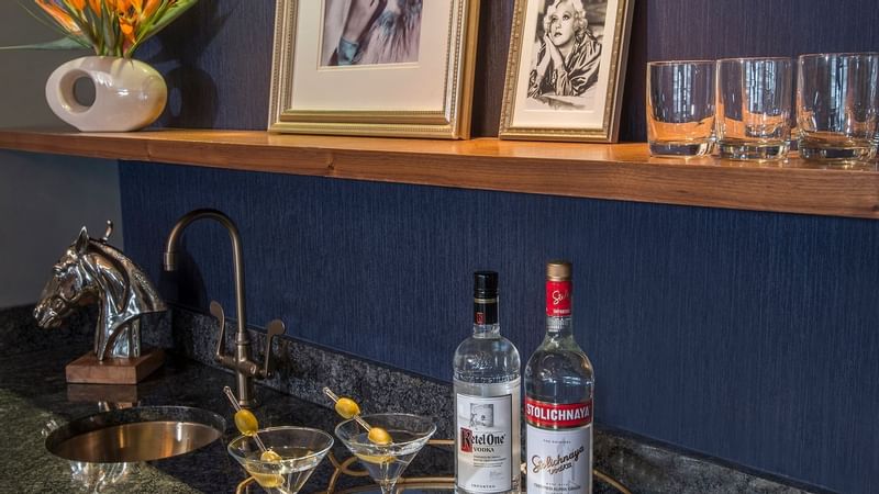 A bar setup with a bottle of vodka and two glasses in Randolph Suite at Warwick New York