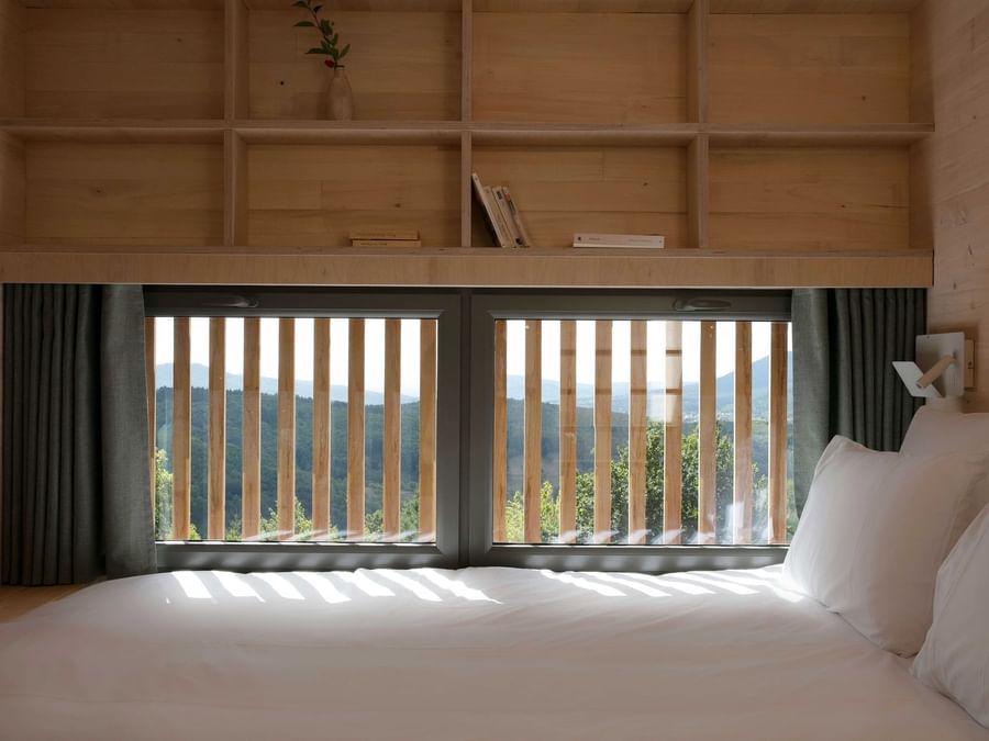 A bed with mountain view window at The Originals Hotels