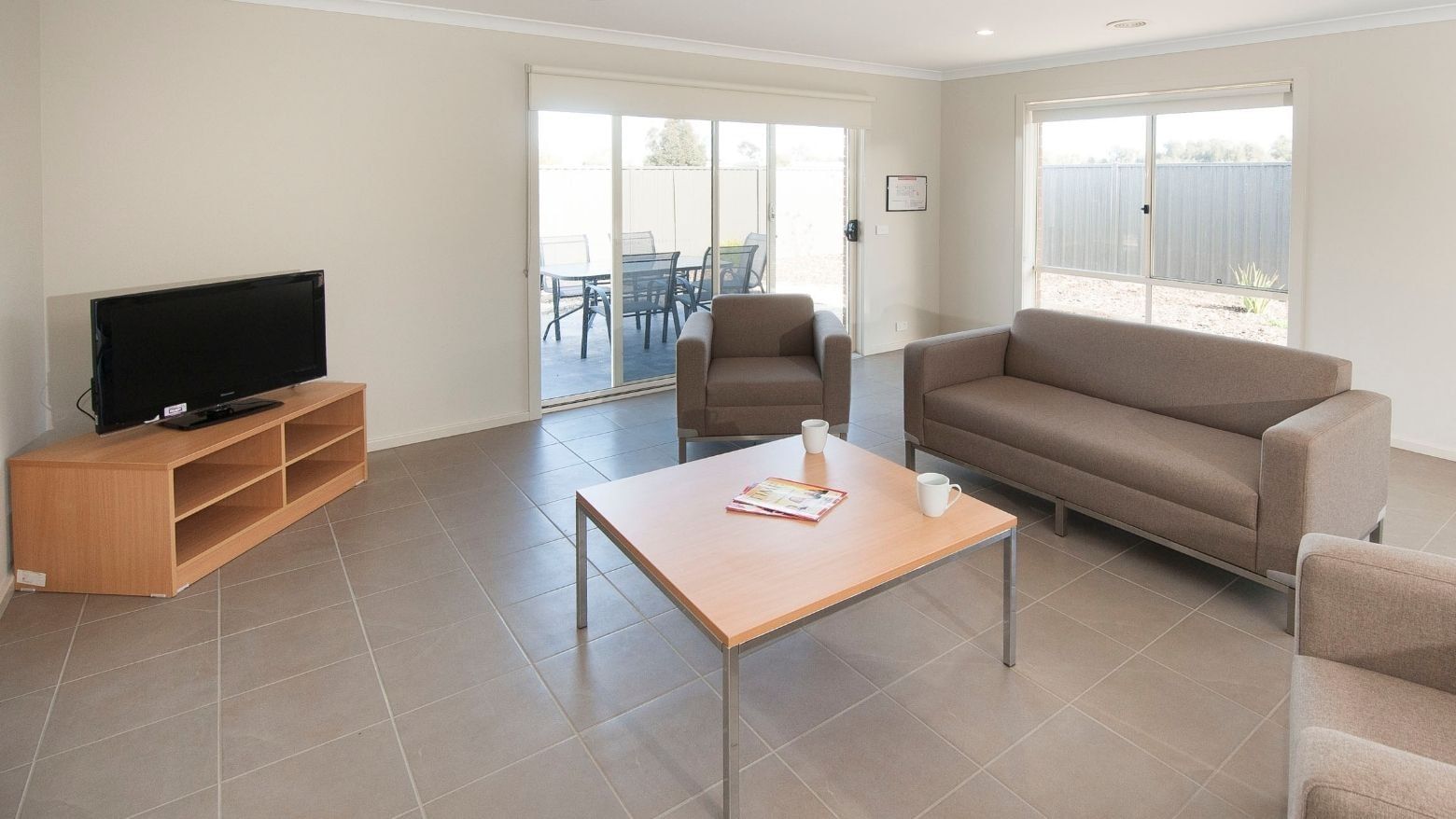 Living room with couch, coffee table, TV, and patio at La Trobe University Regional Housing – Shepparton.