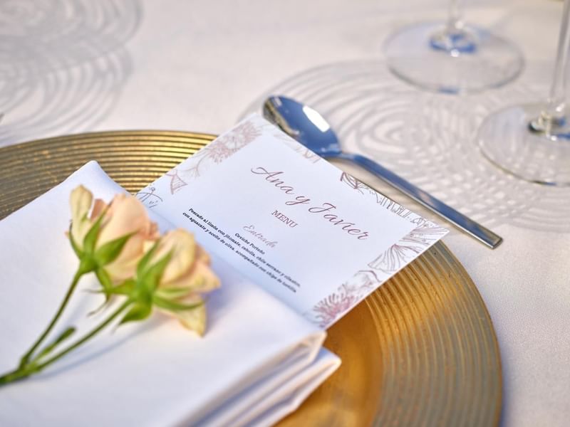 A wedding invitation & roses on a table at Live Aqua Resorts