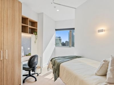 Modern bedroom with wooden furniture, desk, and window at UniLodge Brisbane City.
