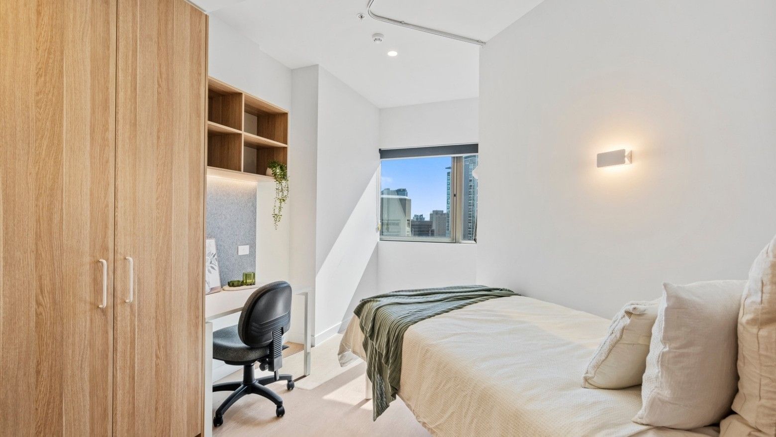 Modern bedroom with wooden furniture, desk, and window at UniLodge Brisbane City.