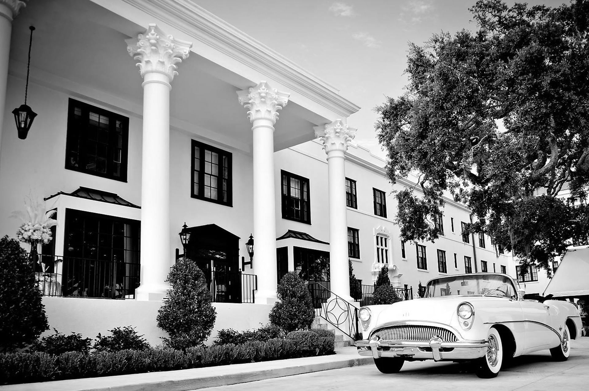 A classic white building with tall columns and a vintage car parked in front of The White House Hotel