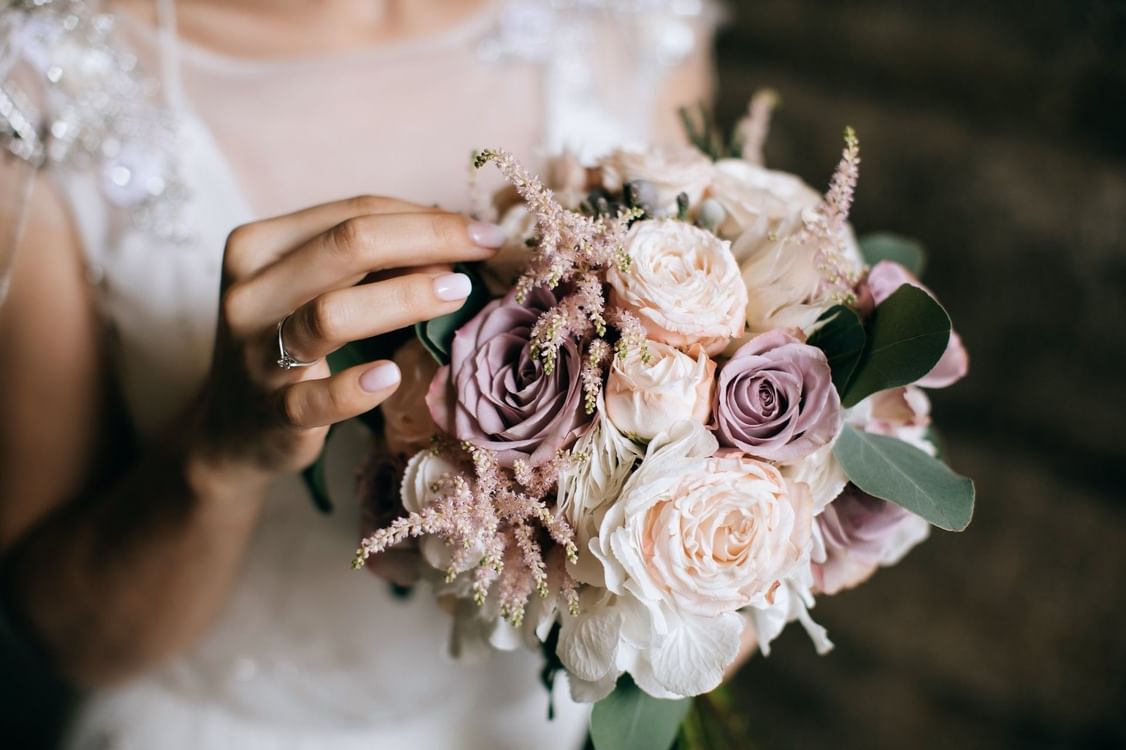 Bride holding a bouquet with pink roses and green leaves in Meeting Room A at Warwick Hotel Jeddah