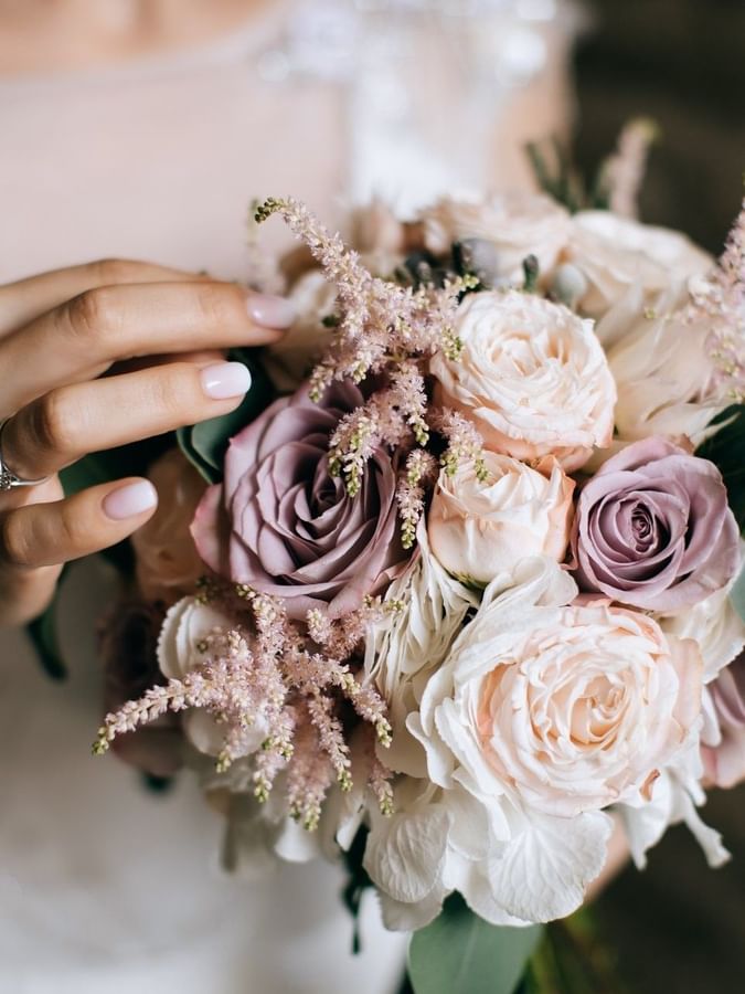 Bride holding a bouquet with pink roses and green leaves in Meeting Room A at Warwick Hotel Jeddah