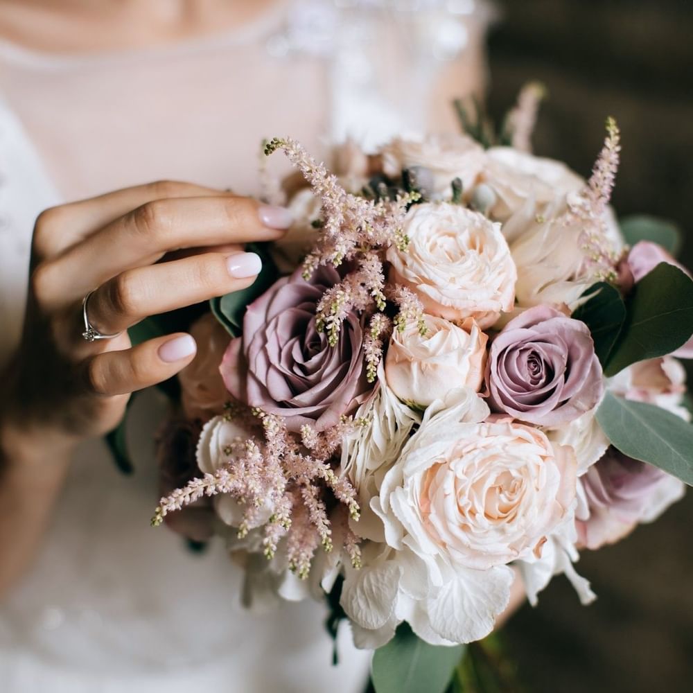 Bride holding a bouquet with pink roses and green leaves in Meeting Room A at Warwick Hotel Jeddah