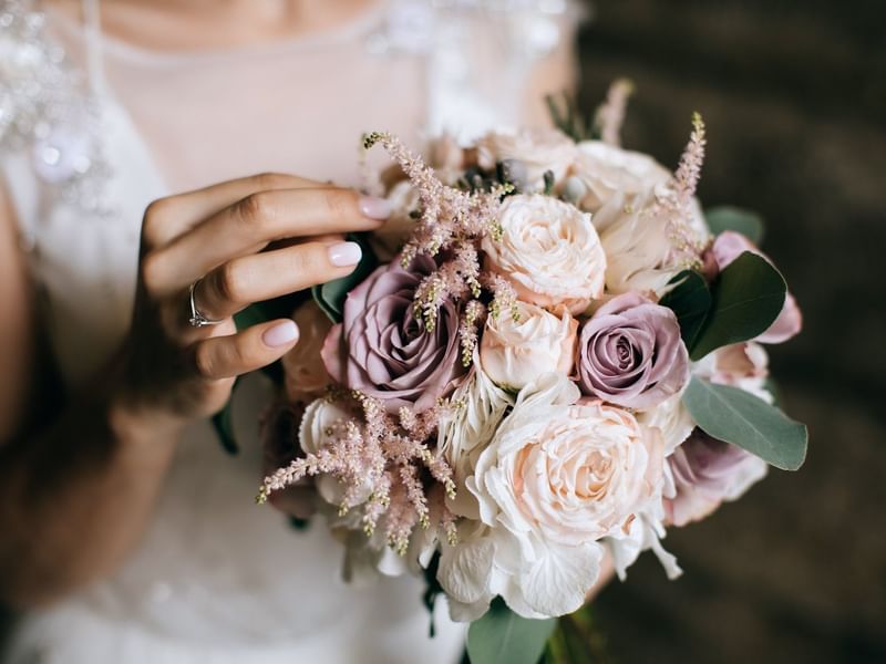Bride holding a bouquet with pink roses and green leaves in Meeting Room A at Warwick Hotel Jeddah