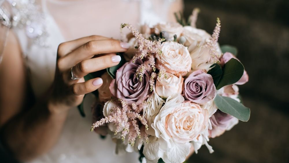 Bride holding a bouquet of pink roses and green leaves in Meeting Room C (A+B) at Warwick Hotel Jeddah