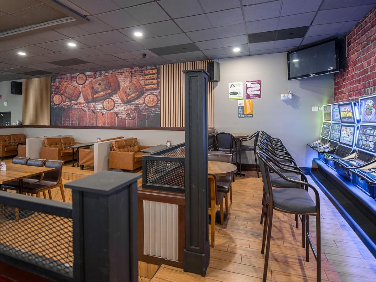 Interior of The Den Pub with seating and slot machines.