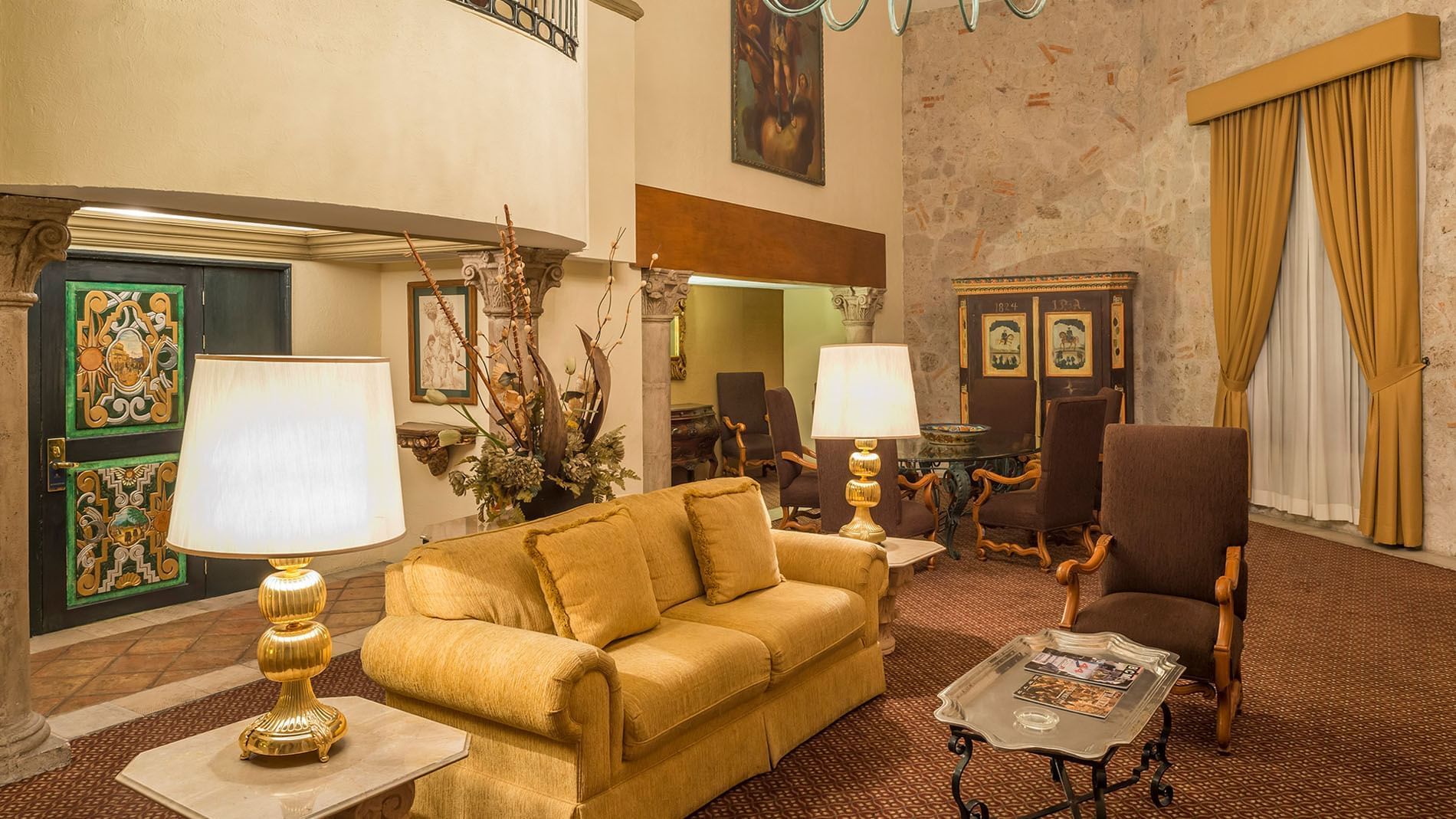 King Presidential Suite grand living area with a gold sofa, high ceilings, and stone walls at Quinta Real Aguascalientes