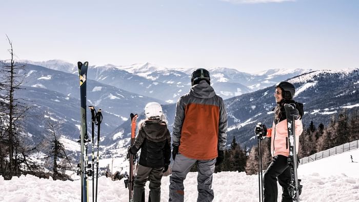 Three skiers standing with equipment, overlooking snowy mountains near Falkensteiner Club Funimation Katschberg