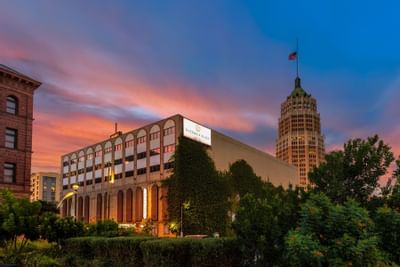 Exterior view of The Riverwalk Plaza Hotel at evening, surrounded by lush greenery