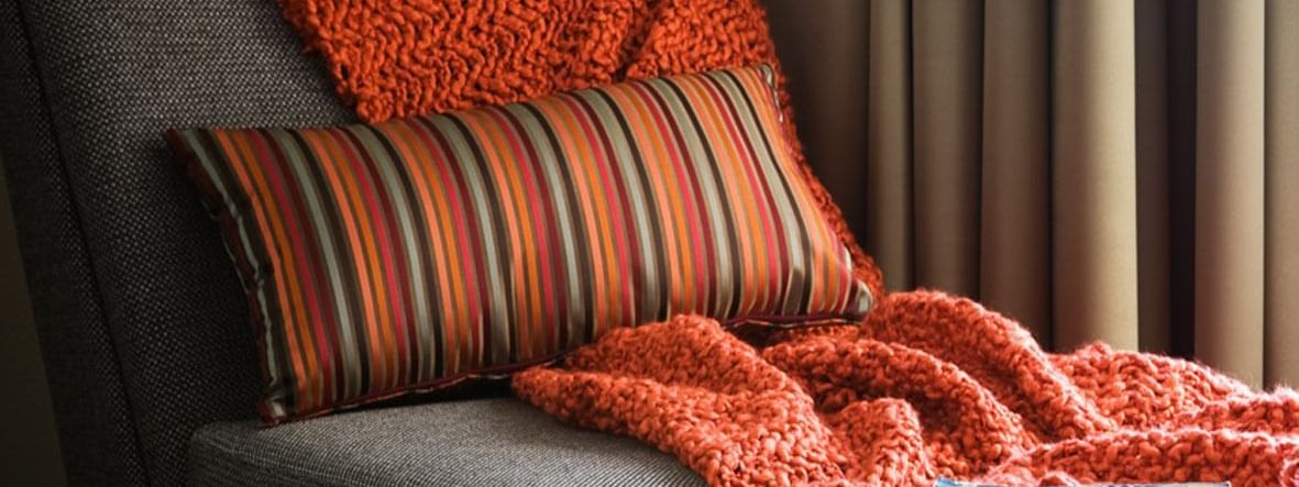 Cozy corner of an Executive Room with a couch and orange knit blanket at Novotel Sydney International Airport