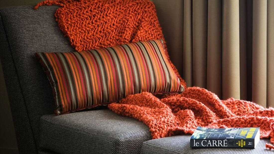 Cozy corner of an Executive Room with a couch and orange knit blanket at Novotel Sydney International Airport