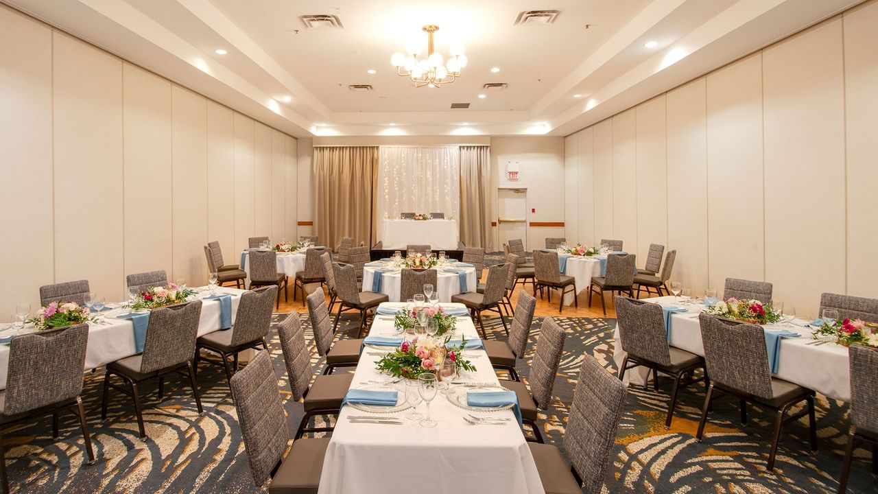 Banquet hall with round tables, floral arrangements, and a chandelier.