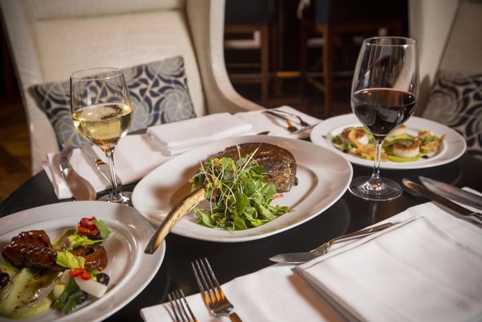 A table with plates of delicious food & glasses of wine at The Diplomat Resort