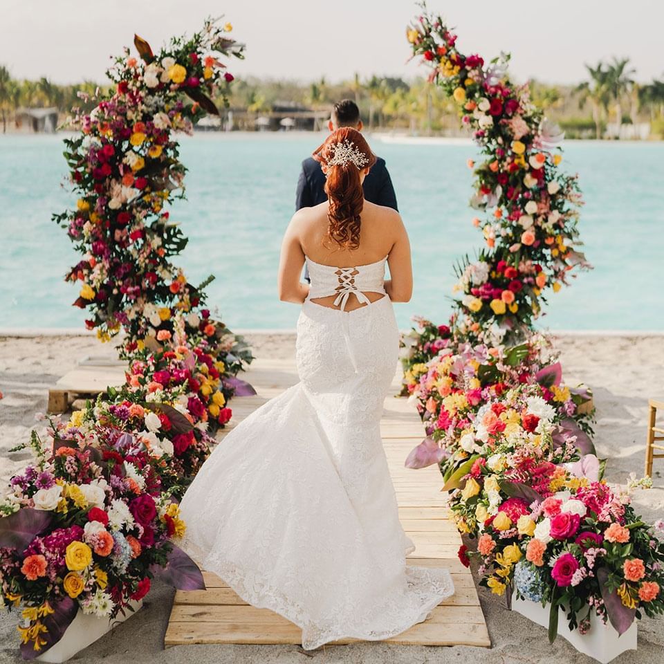 Couple by the floral wedding arch at Playa Blanca Beach Resort