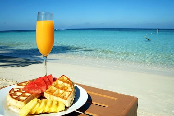 Waffles & orange juice on a table by the beach at Infinity Bay