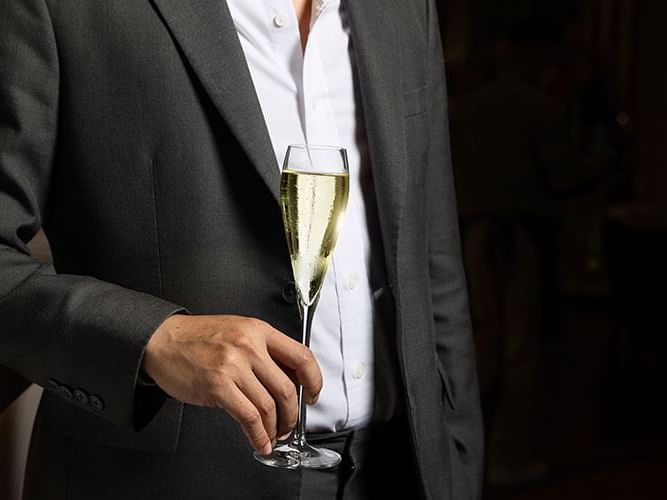 A man in a suit elegantly holds a glass of champagne, exuding sophistication and celebration