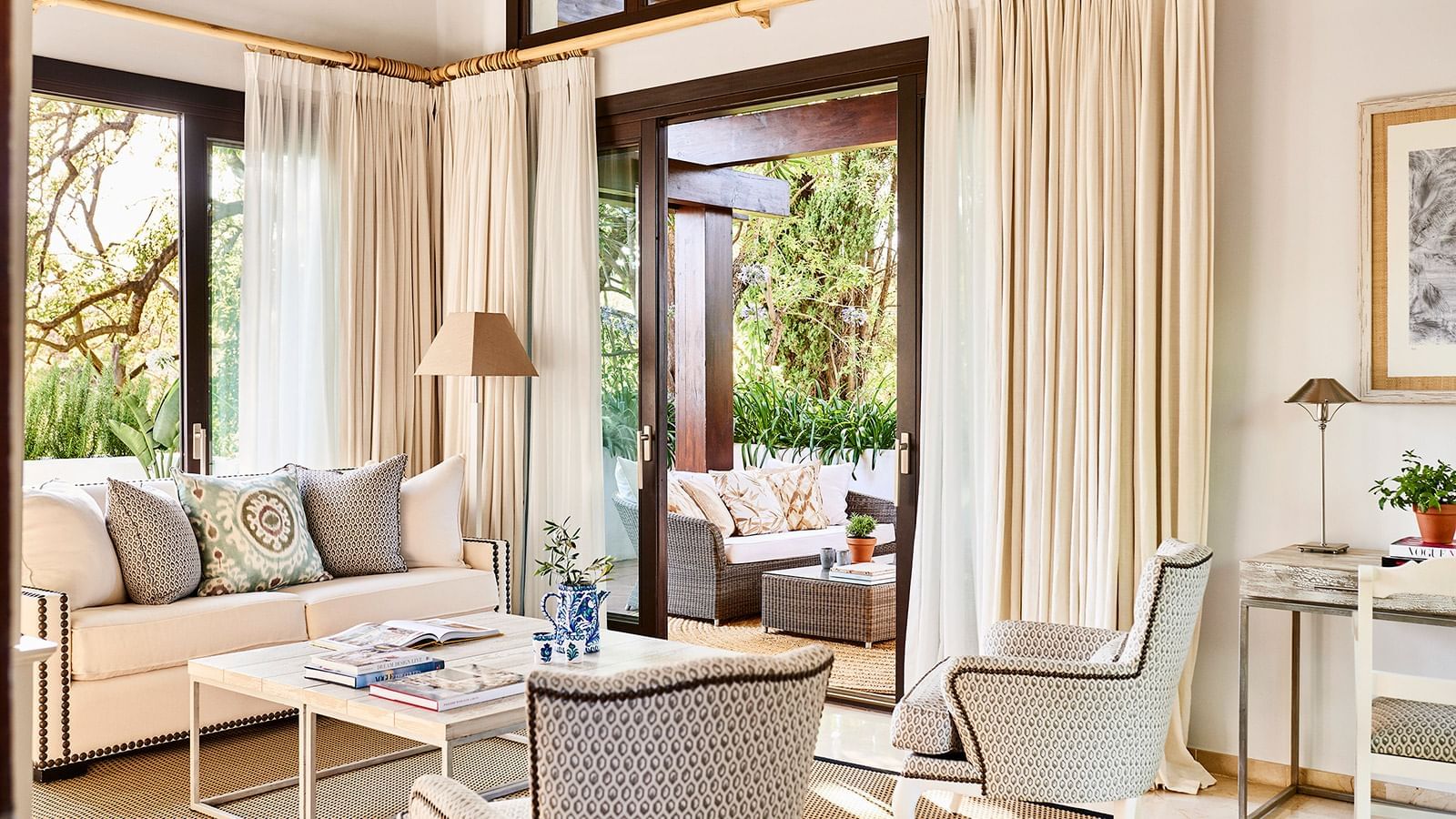 La Concha Suite with patterned chairs & sliding glass doors opening to a covered outdoor lounge at Marbella Club