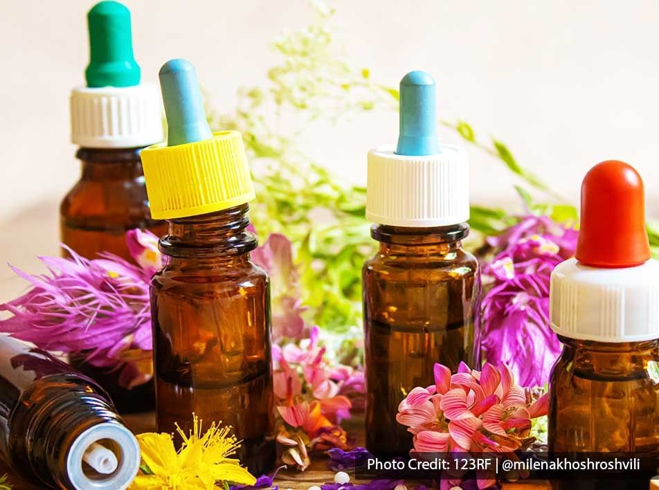 an array of essential oils with colourful flower petals as decoration - Lexis Port Dickson