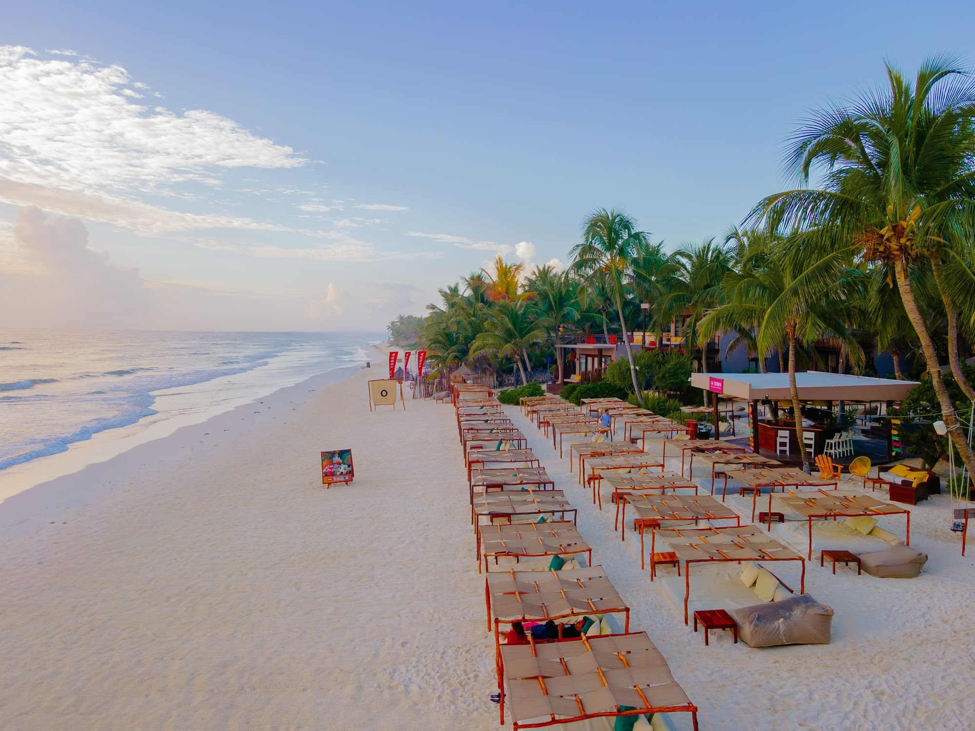La Zebra Tulum beach club daybeds on white sand facing the Caribbean Sea.
