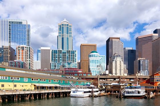 White ferries docked by a colorful pier building under a cloudy sky near Paramount Hotel Seattle